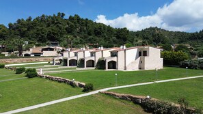 A stone building with multiple arches and a tiled roof, surrounded by a well-maintained lawn and a pathway.
