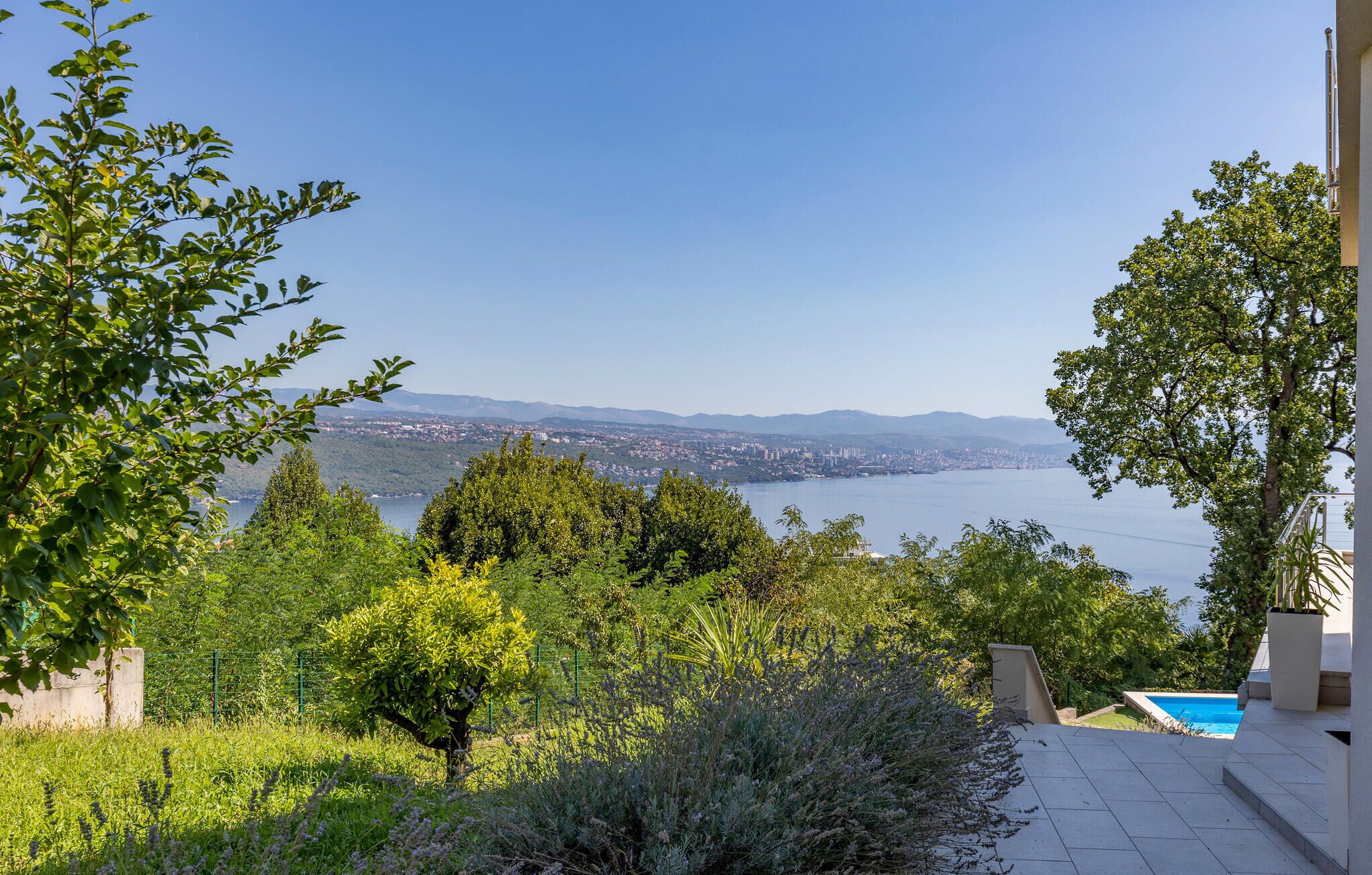 A terrace with a pool, overlooking a lake and cityscape.