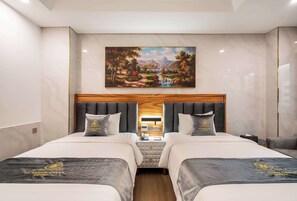 Quarto de hotel com duas camas, um quadro de paisagem e cabeceira de madeira.
