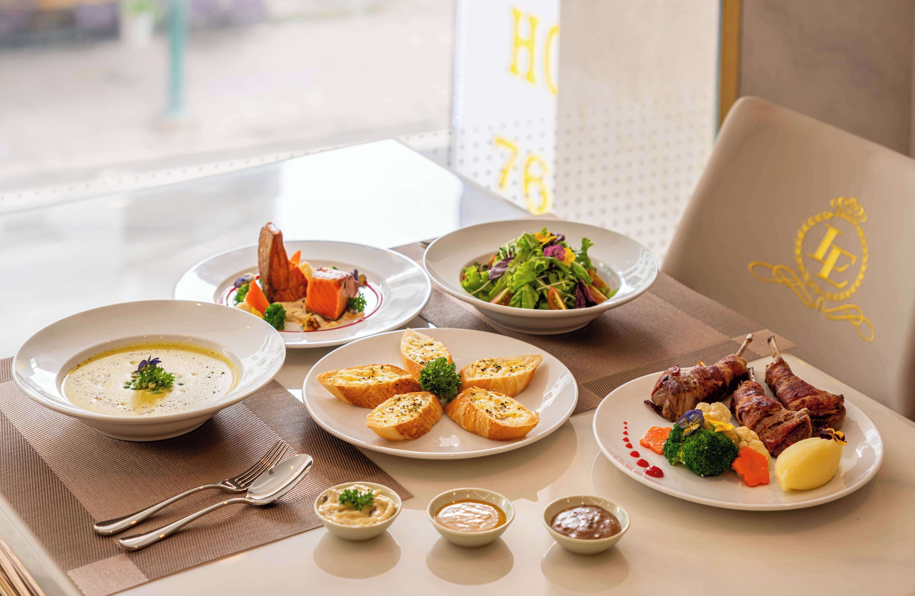 A dining table with various dishes including soup, roasted meat, and vegetables.
