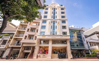 A multi-story hotel with a grand entrance, balconies, and a clear view of the sky.