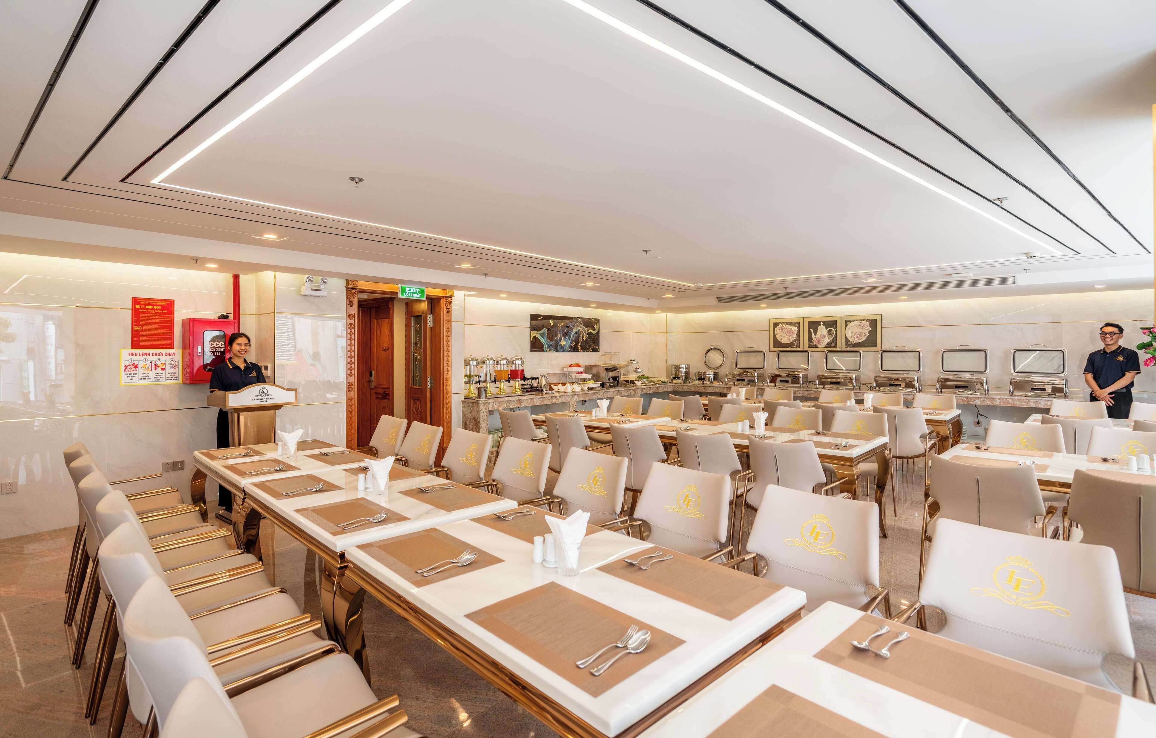 A hotel conference room with long tables, chairs, and a buffet area.