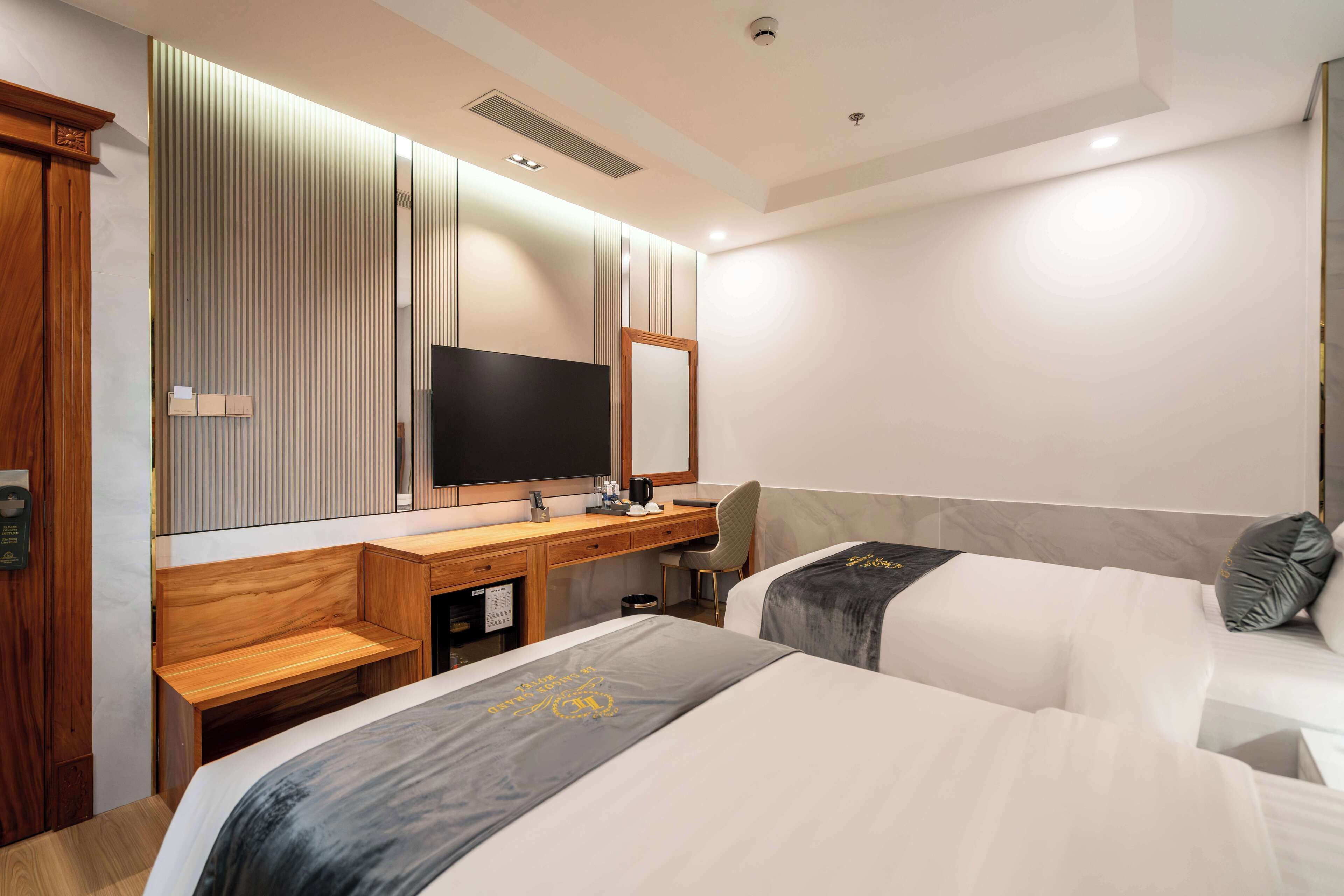 Ett hotellrum med två sängar, ett skrivbord i trä, en tv och en spegel.