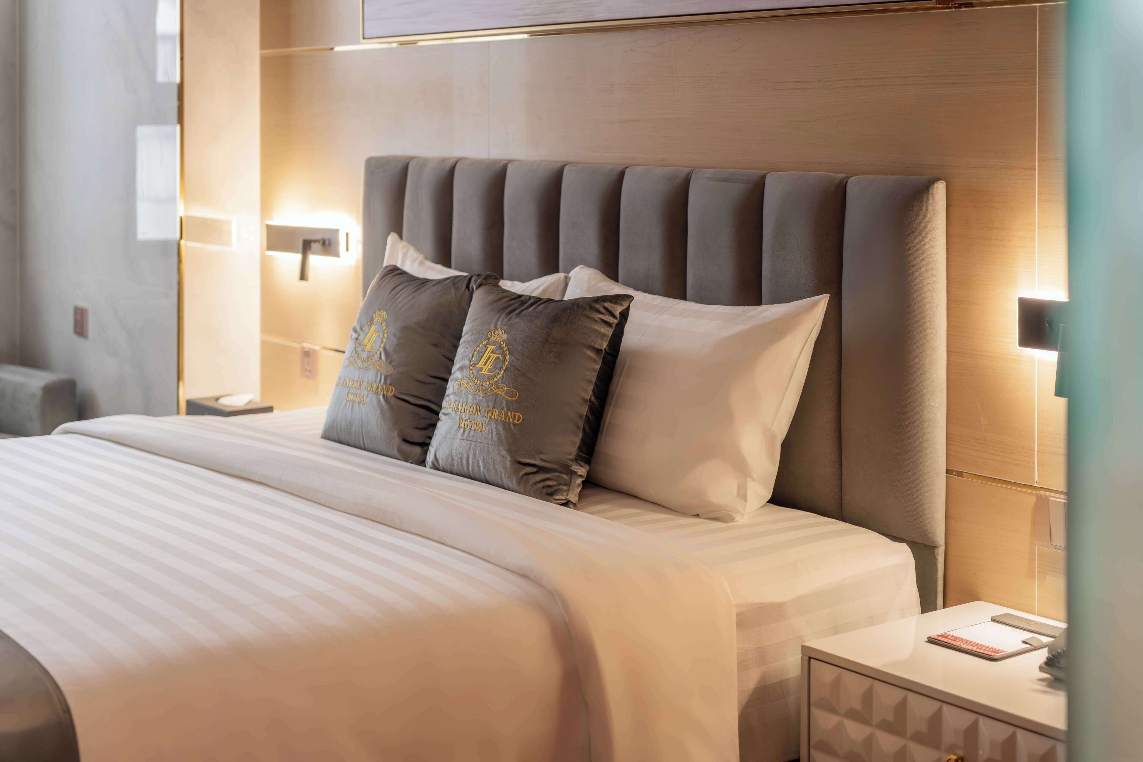 Een hotelkamer met een groot bed, een hoofdbord, twee bedlampen en een nachtkastje met een boek en een telefoon.