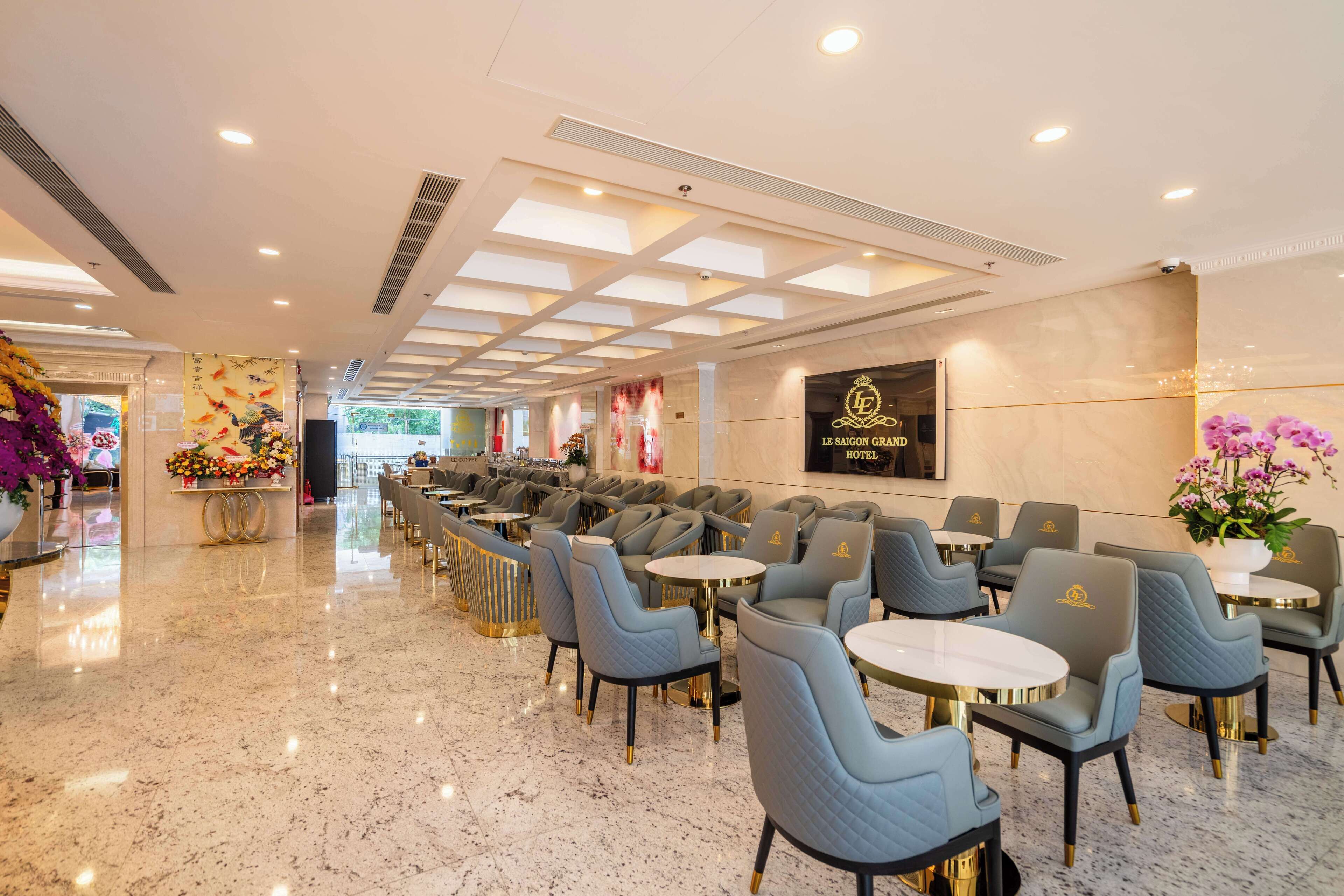 Un hall d’hôtel avec une longue rangée de sièges, un comptoir d’accueil et une enseigne indiquant le nom de l’hôtel.