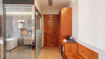 A modern bathroom with a glass shower enclosure, a wooden vanity, and a coffee machine on a wooden console.