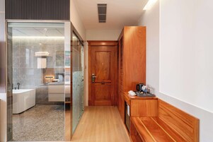 A modern bathroom with a glass shower enclosure, a wooden vanity, and a coffee machine on a wooden console.