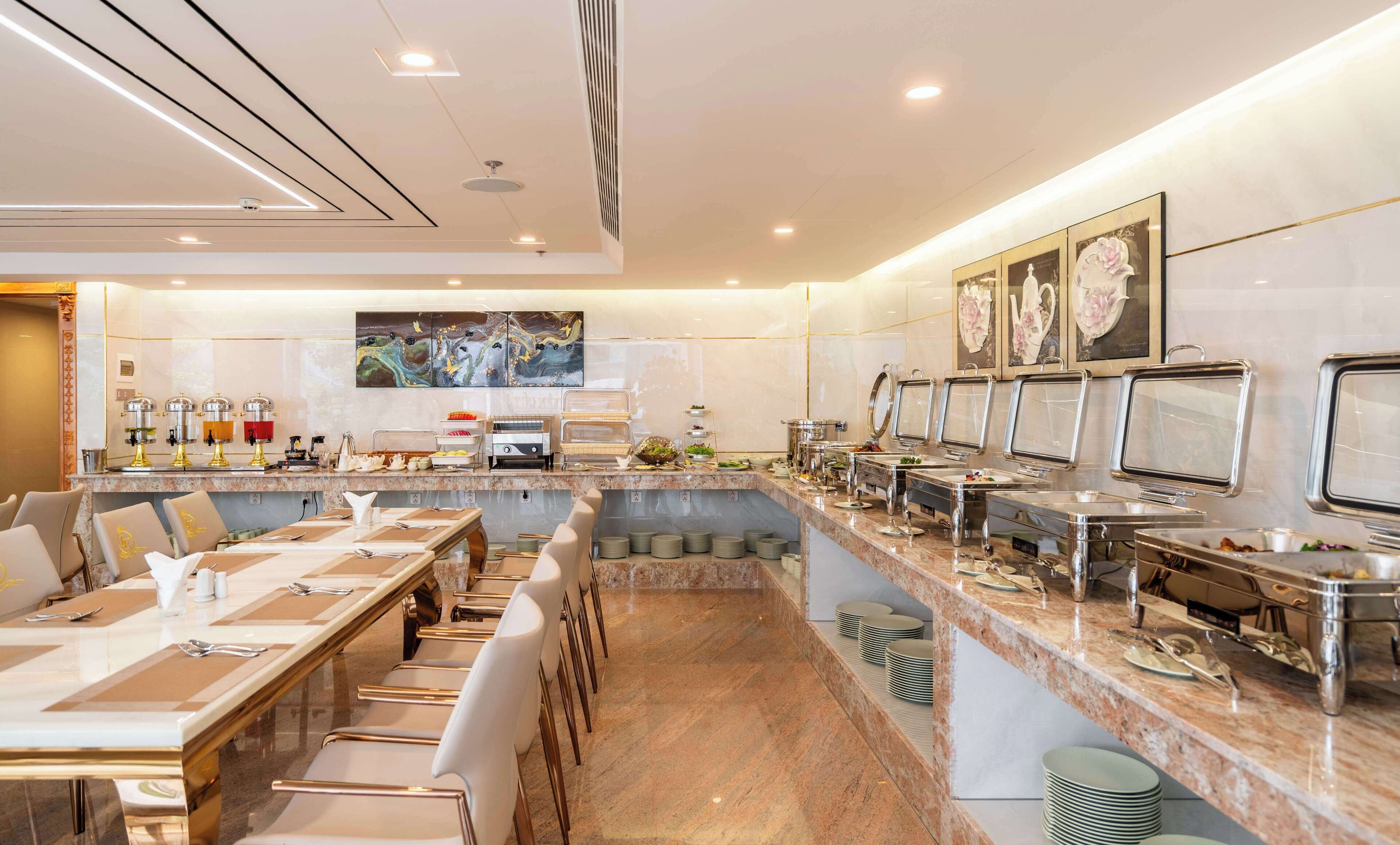 A spacious buffet area with multiple serving stations, a long dining table with chairs, and a wall adorned with artwork.