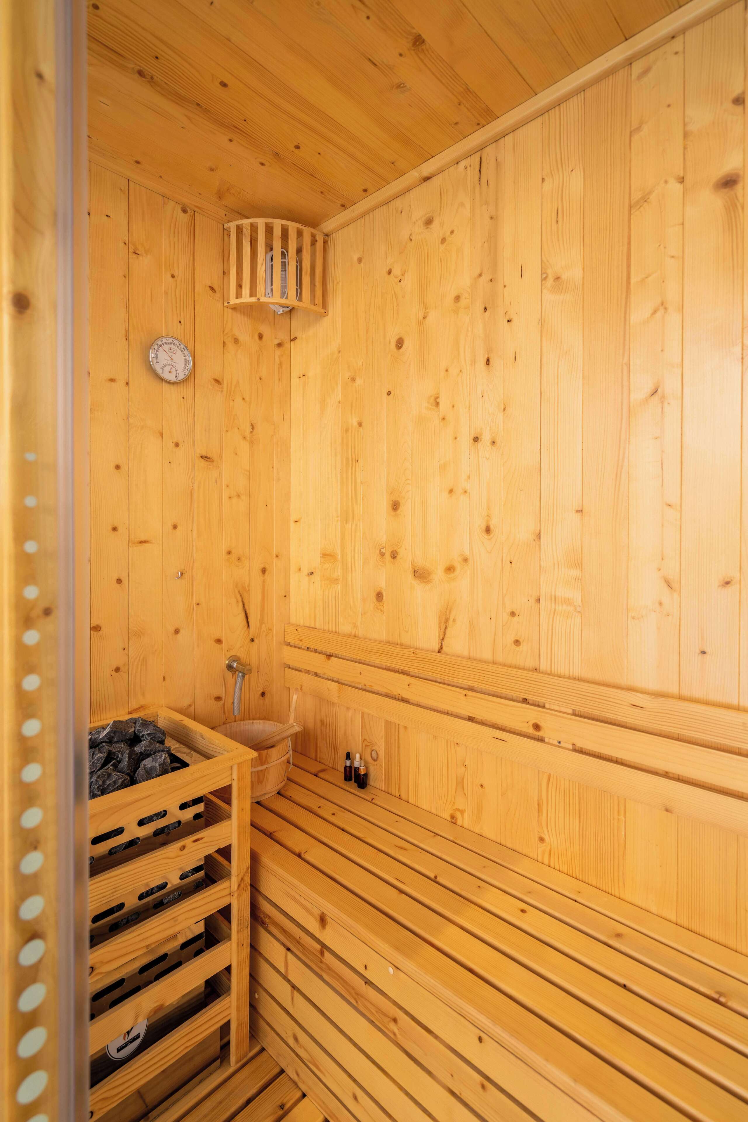 Un sauna en bois avec un banc, un petit lavabo et un radiateur.