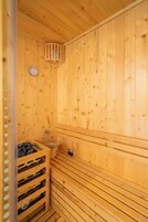 A wooden sauna with a bench, a small sink, and a heater.