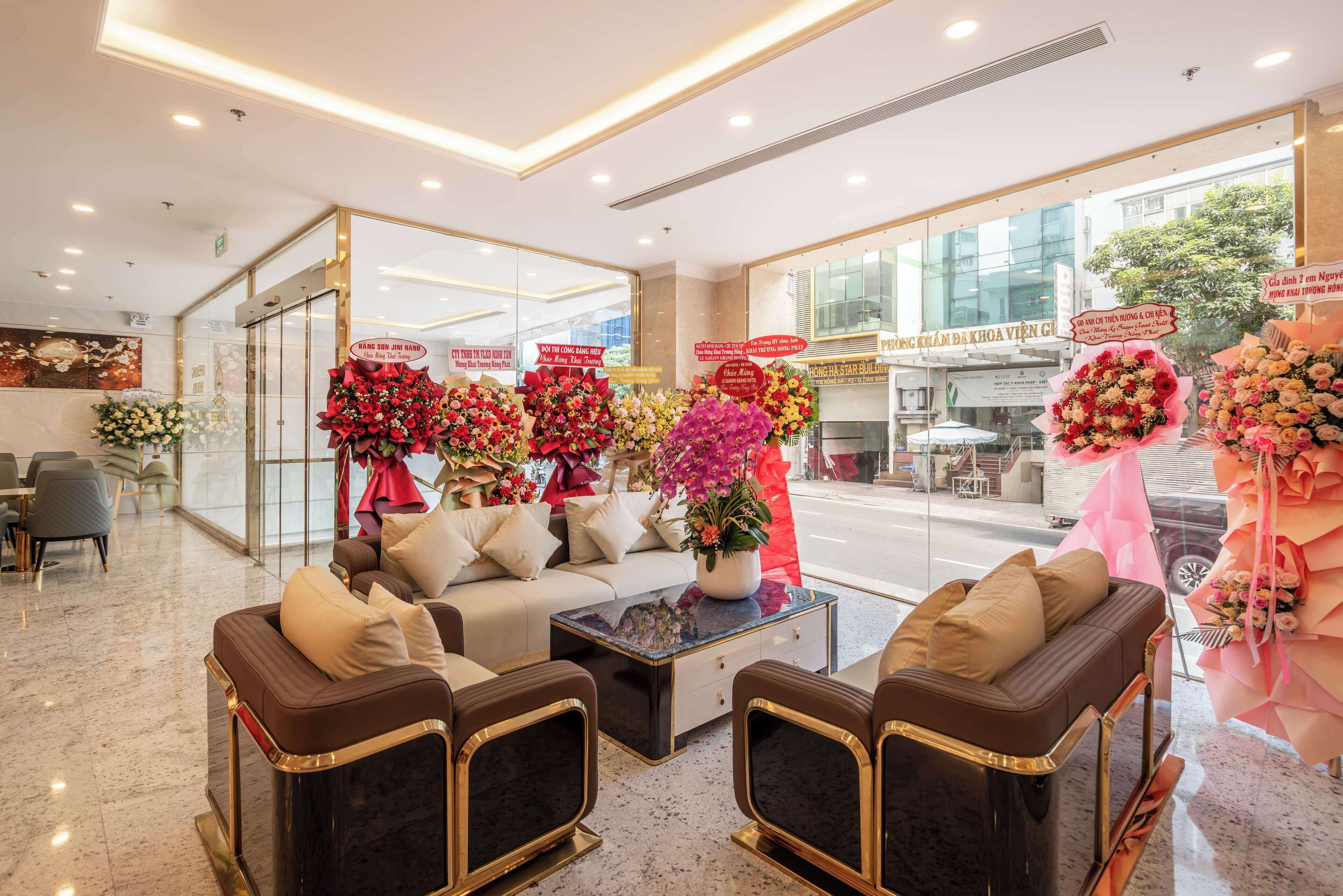 Eine Hotelhalle mit Sitzgelegenheiten, einem Empfangsbereich und großen Blumenarrangements.