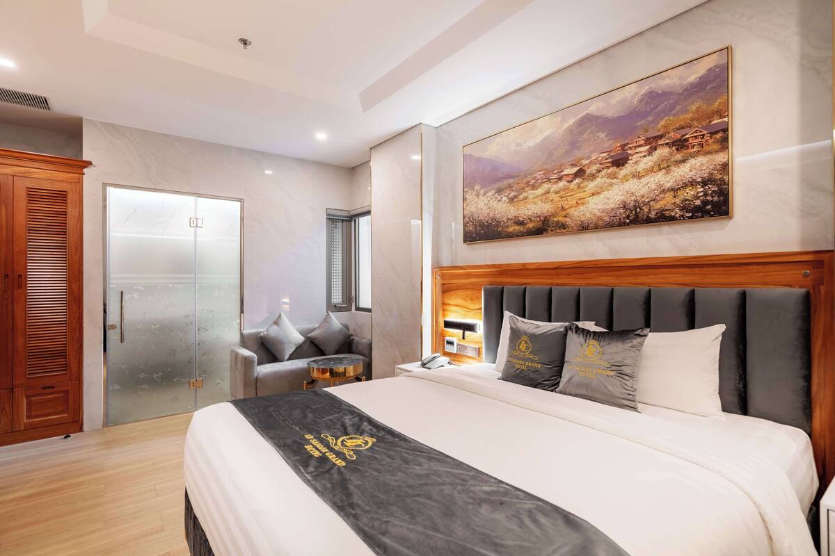 Ein Hotelzimmer mit einem großen Bett, einem Holz-Kopfteil, einem Gemälde an der Wand und einem Schiebetürenschrank.