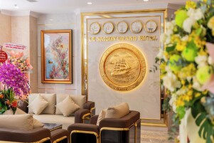 Un hall con mostrador de recepción, zona de estar y una pared decorada con relojes y un emblema dorado.