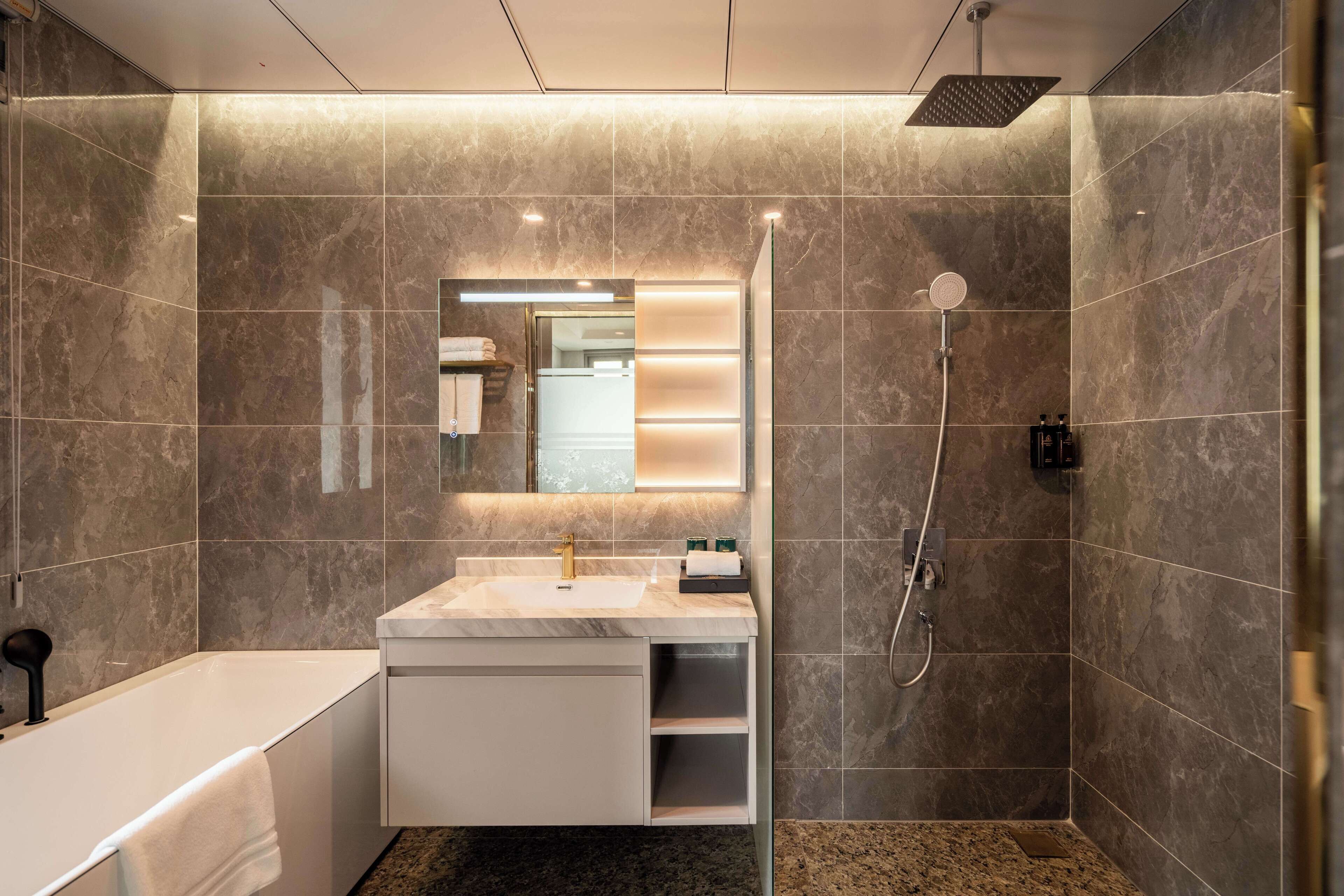 A modern bathroom with a bathtub, a vanity with a mirror, and a shower area.