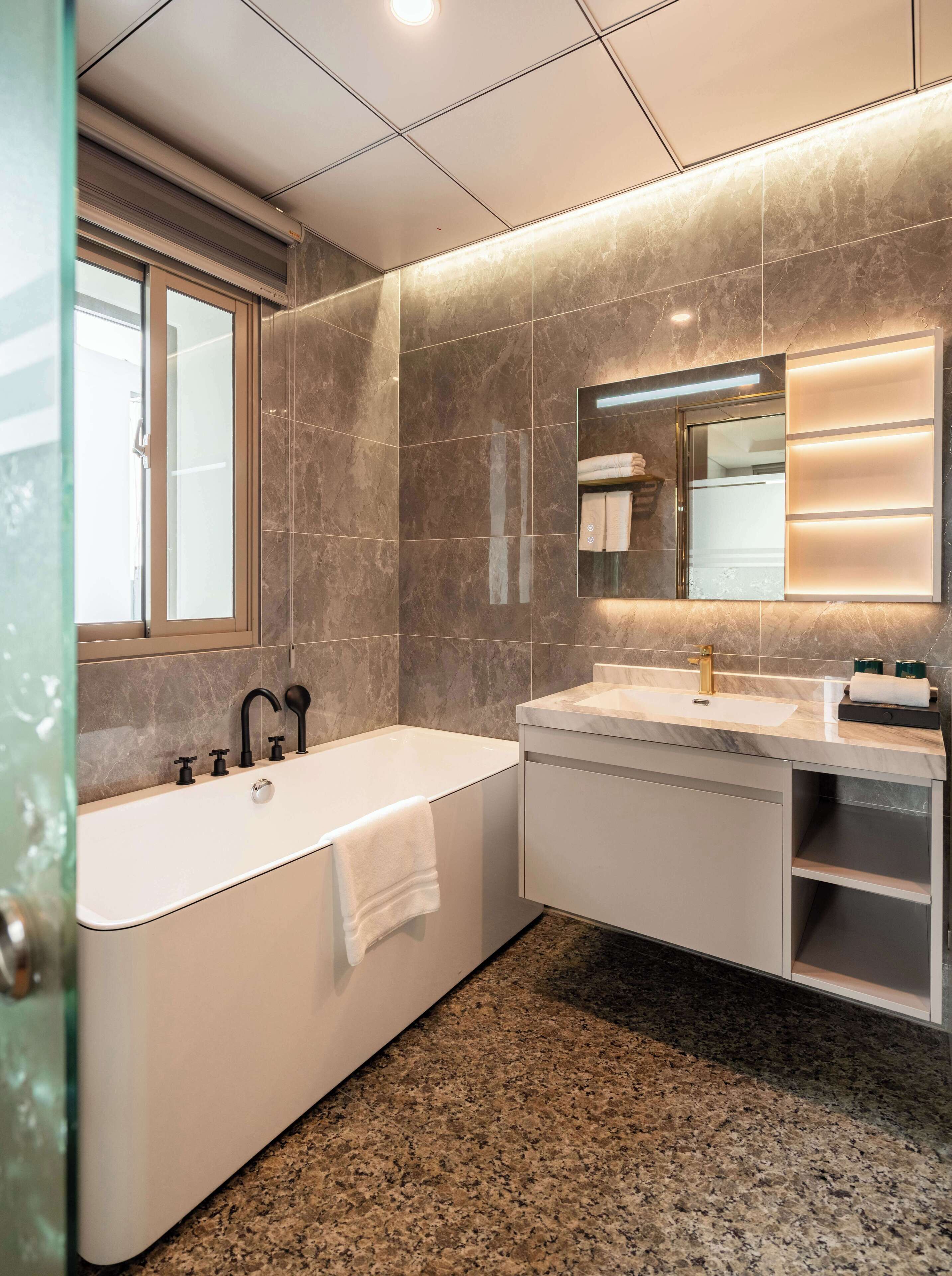 Un baño moderno con una bañera independiente, un tocador con lavabo y un espejo grande.