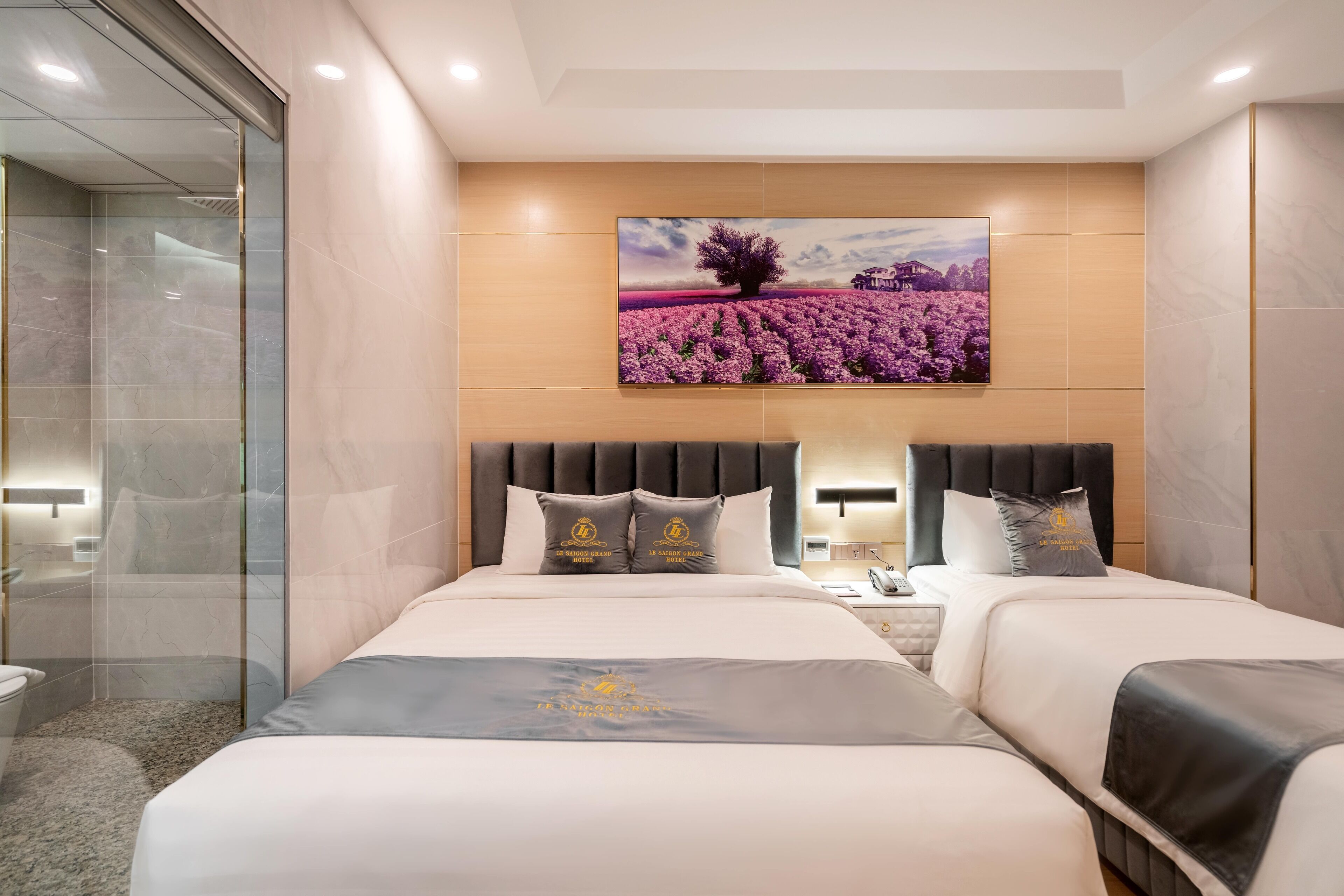 A hotel room with a large bed, a headboard with a decorative panel, a bedside table, and a wall-mounted painting.