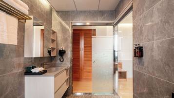 A modern bathroom with a marble floor, a wooden door, and a glass shower enclosure.