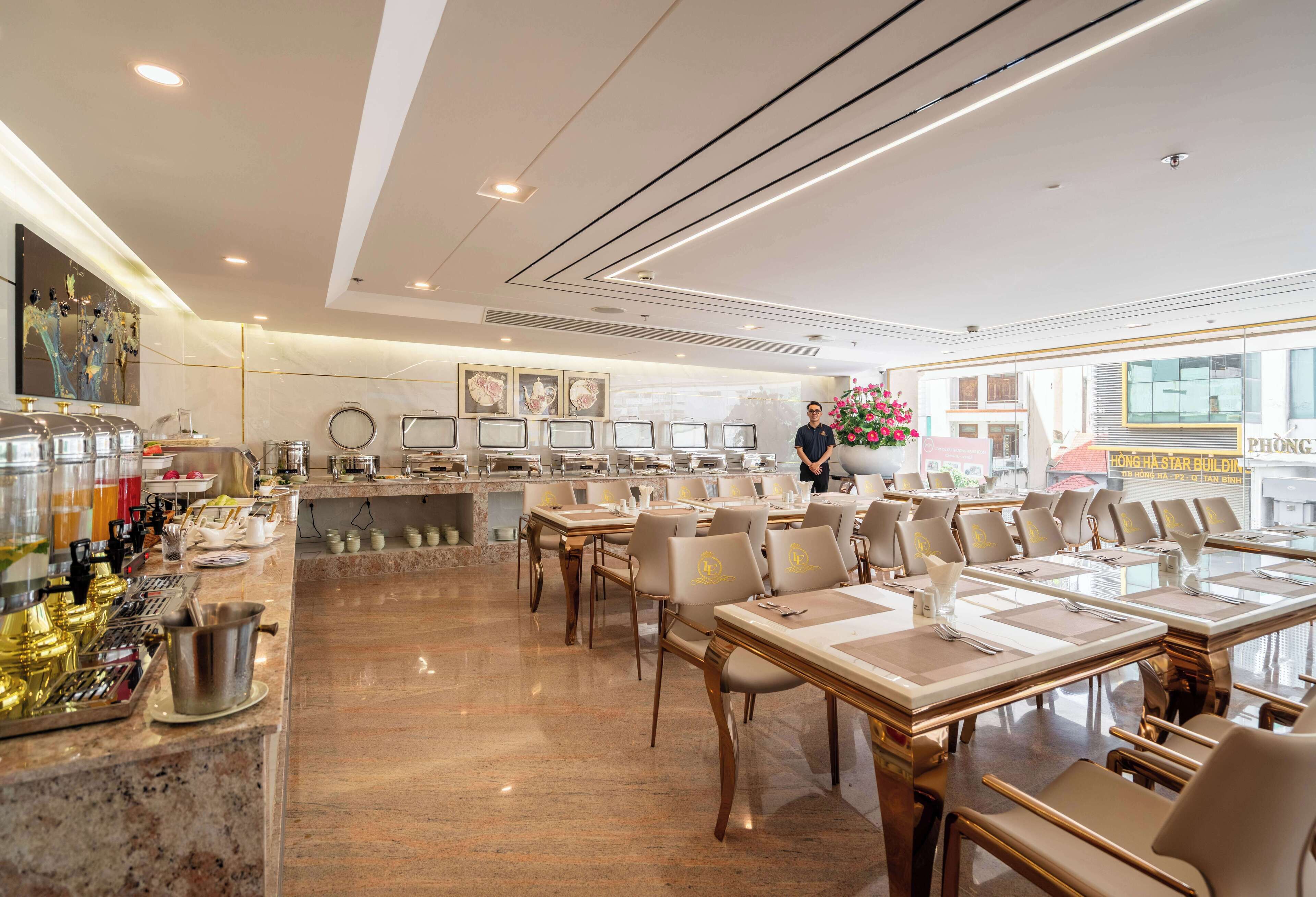Un restaurante amplio con suelos de mármol, mesas y sillas ordenadas, una zona de bar con diversas bebidas y obras de arte enmarcadas en las paredes.