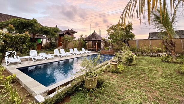 Una piscina con sillas de descanso, rodeada de follaje y arquitectura tradicional.