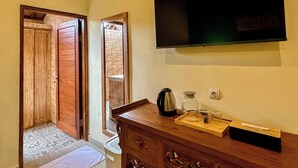 Una habitación con un armario de madera, un televisor montado en la pared, una cafetera y una mesita con una bandeja.