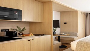 A compact kitchenette with a Bosch microwave, a coffee maker, and a small dining area with a sofa and a table. - Luxurious studio -Panthéon/Jardin de Luxembourg (Paris)