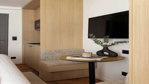 A compact hotel room with a bed, a seating area with a small table, a flat-screen TV mounted on the wall, and a microwave above the seating area. - Luxurious studio -Panthéon/Jardin de Luxembourg (Paris)
