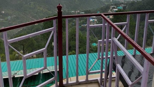 Un balcon offrant une vue sur un paysage montagneux et une ville lointaine.