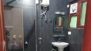 Une salle de bain avec une douche à parois de verre, un lavabo sur colonne et des toilettes.