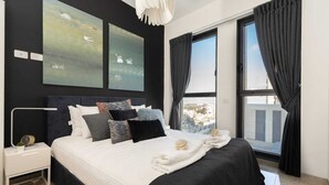 A modern bedroom with a large bed, a nightstand, a wall-mounted lamp, and two abstract paintings. - JTower  Magical 4BR Parking with amazing view, city center (Jerusalem)