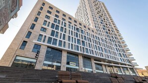 A modern high-rise building with a prominent glass facade, multiple balconies, and a series of steps leading to the entrance. - JTower  Magical 4BR Parking with amazing view, city center (Jerusalem)