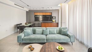 Una sala moderna con un sofá modular, una zona de comedor y una cocina al fondo.