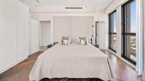 Un dormitorio espacioso con una cama grande, vistas a la ciudad y un diseño moderno.