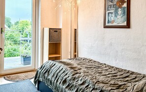 Une chambre à coucher avec un grand lit, une armoire, une porte donnant sur un balcon et un tableau encadré au mur.