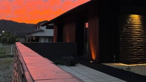 A modern building with a flat roof and large windows, set against a sunset sky with pink clouds. - Limited to one pair per day! The entire building is reserved for private use! A luxurious inn designed in a modern Japanese style! You can enjoy your private time in the nature of Amami Oshima with a large projector. ⭐︎ (龍郷町)