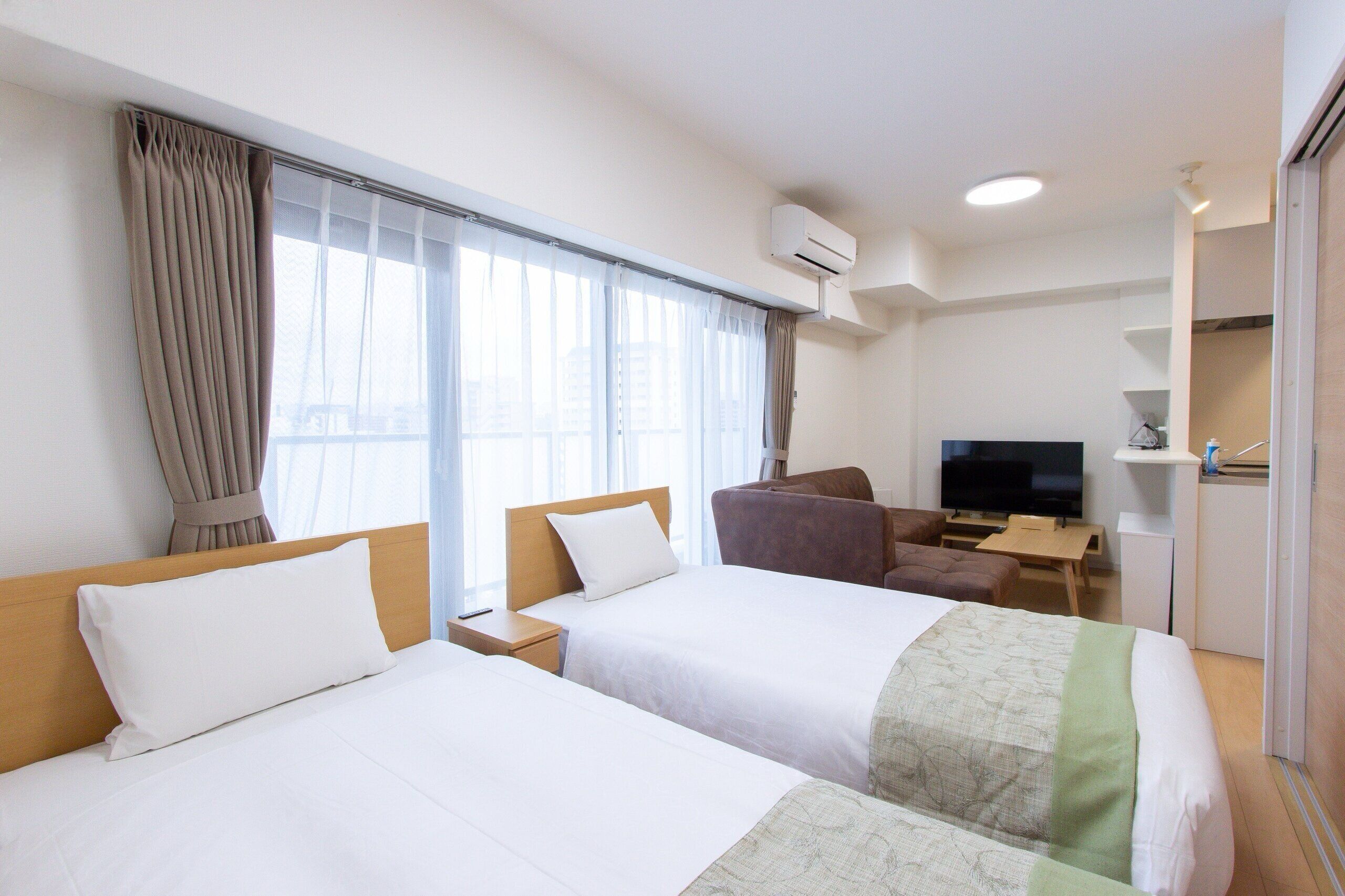 A hotel room with two beds, a TV, a desk, and a chair.