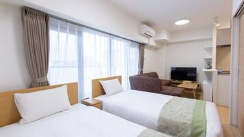 A hotel room with two beds, a TV, a desk, and a chair.