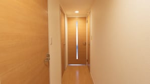 A narrow hallway with wooden doors on both sides and a light source at the end. - Felice Hakata (Fukuoka)