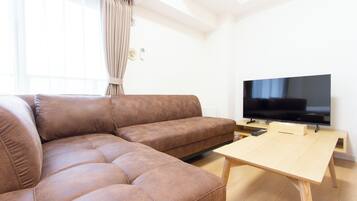 Ein Wohnzimmer mit einem braunen Ecksofa, einem Holztisch und einem Flachbildfernseher.