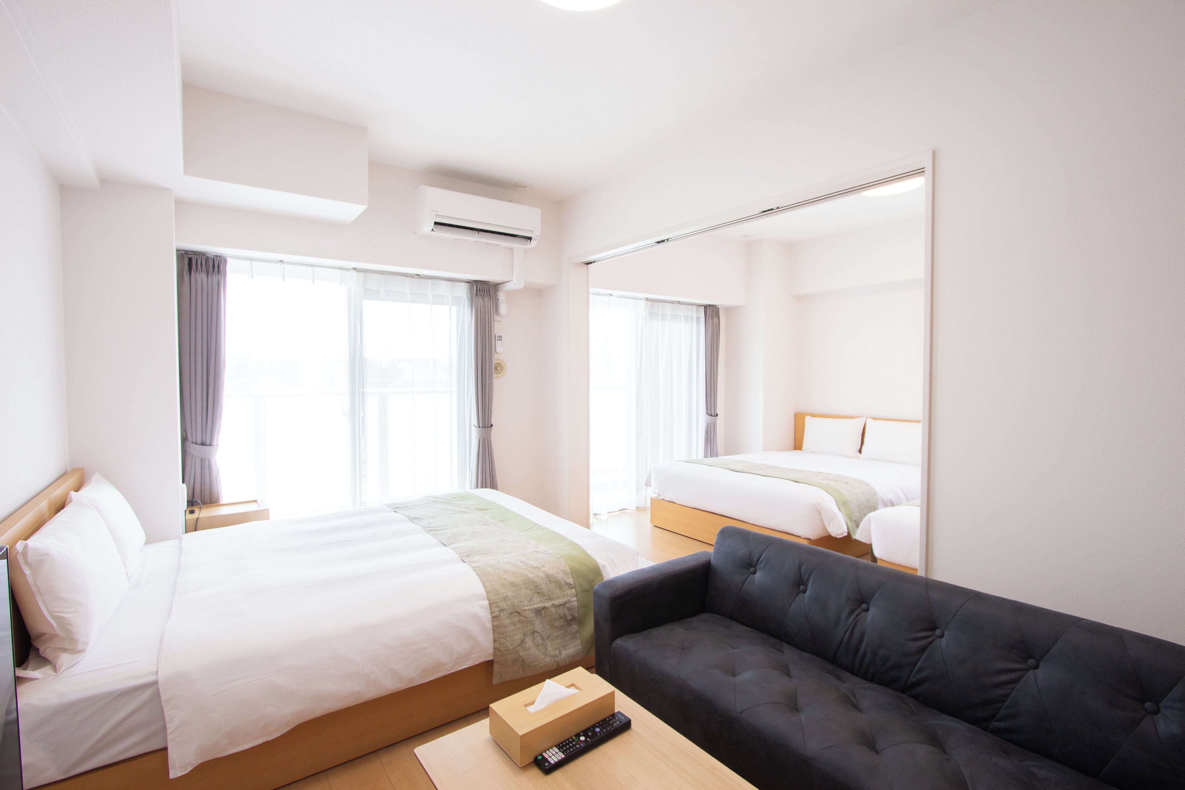 Quarto de hotel com duas camas, um sofá e um espelho.