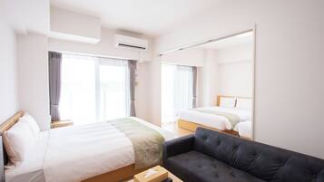 Quarto de hotel com duas camas, um sofá e um espelho.