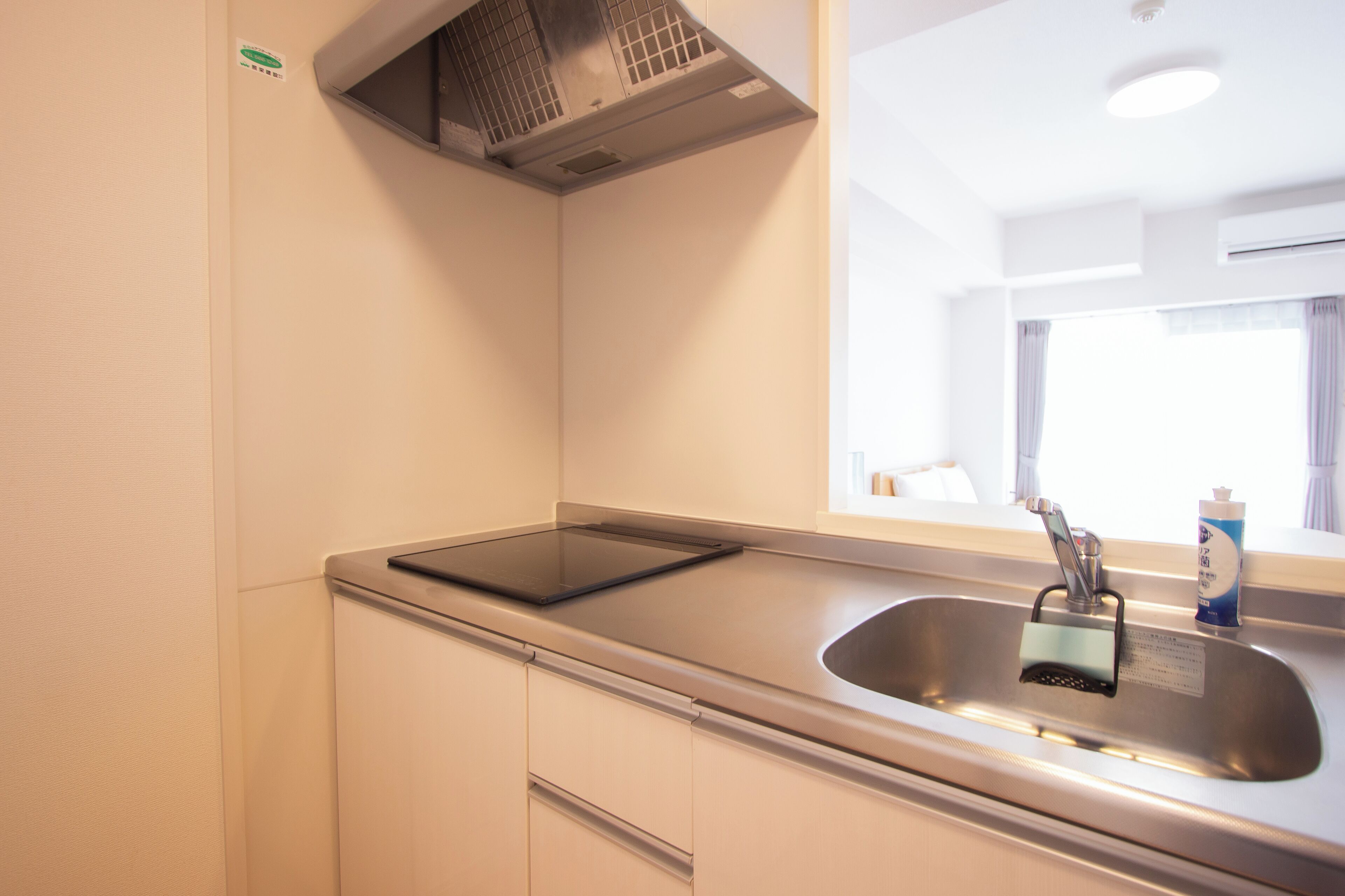 A modern kitchen with a stainless steel sink, a built-in stove, and a window above the sink.