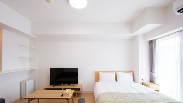 A hotel room with a bed, a TV, a desk, a chair, and a window with curtains. - Felice Hakata (Fukuoka)