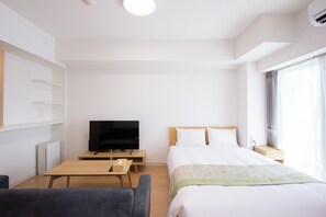 A hotel room with a bed, a TV, a desk, a chair, and a window with curtains. - Felice Hakata (Fukuoka)