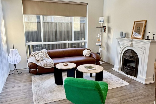 Your serene getaway awaits. Unwind in this cozy living room, complete with a comfortable leather sofa, a charming fireplace, and plenty of natural light. It's the perfect place to relax and feel at home.