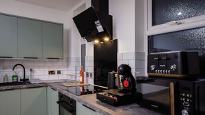 Una cocina moderna con microondas incorporado, cafetera y extractor de aire negro.