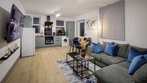 Una sala de estar moderna con un sofá gris, una mesa de centro y un televisor montado en la pared.