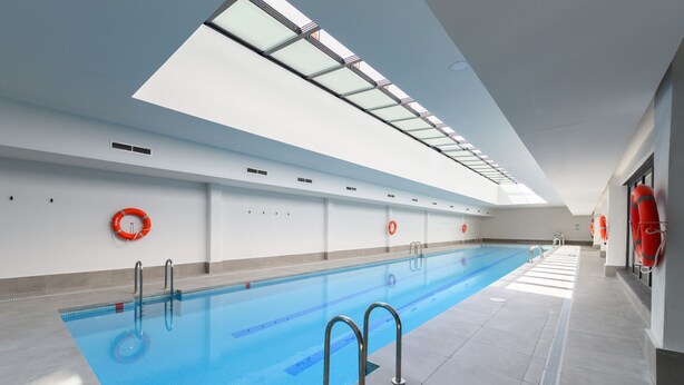 An indoor swimming pool with clear blue water, metal ladders, and red life rings on the walls. - Modern studio apartment with private terrace and excellent communal areas (San Sebastián de los Reyes)