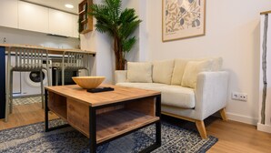 A living room with a sofa, a coffee table, a washing machine, and a large plant. - Modern studio apartment with private terrace and excellent communal areas (San Sebastián de los Reyes)