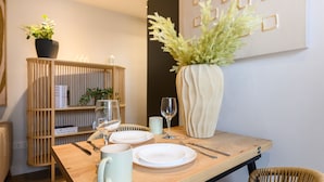 A dining table set with plates, cutlery, and a vase of flowers.