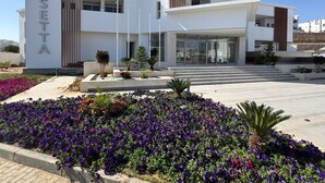 A modern building with the name 'ROSETTA' on the facade, featuring a flat roof, large windows, and a landscaped entrance with purple flowers. - Rosetta Hotel & SPA (Sharm El Sheikh)